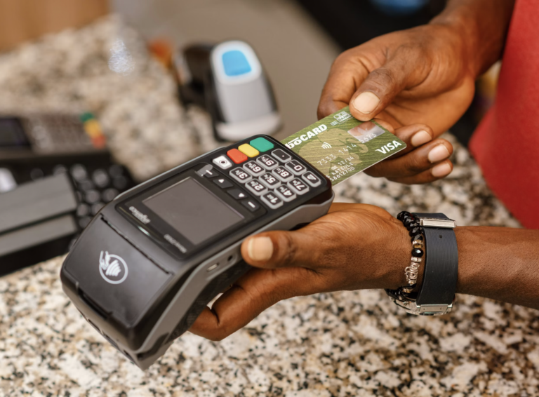 Person inserts a green Visa card into a payment terminal at a checkout.
