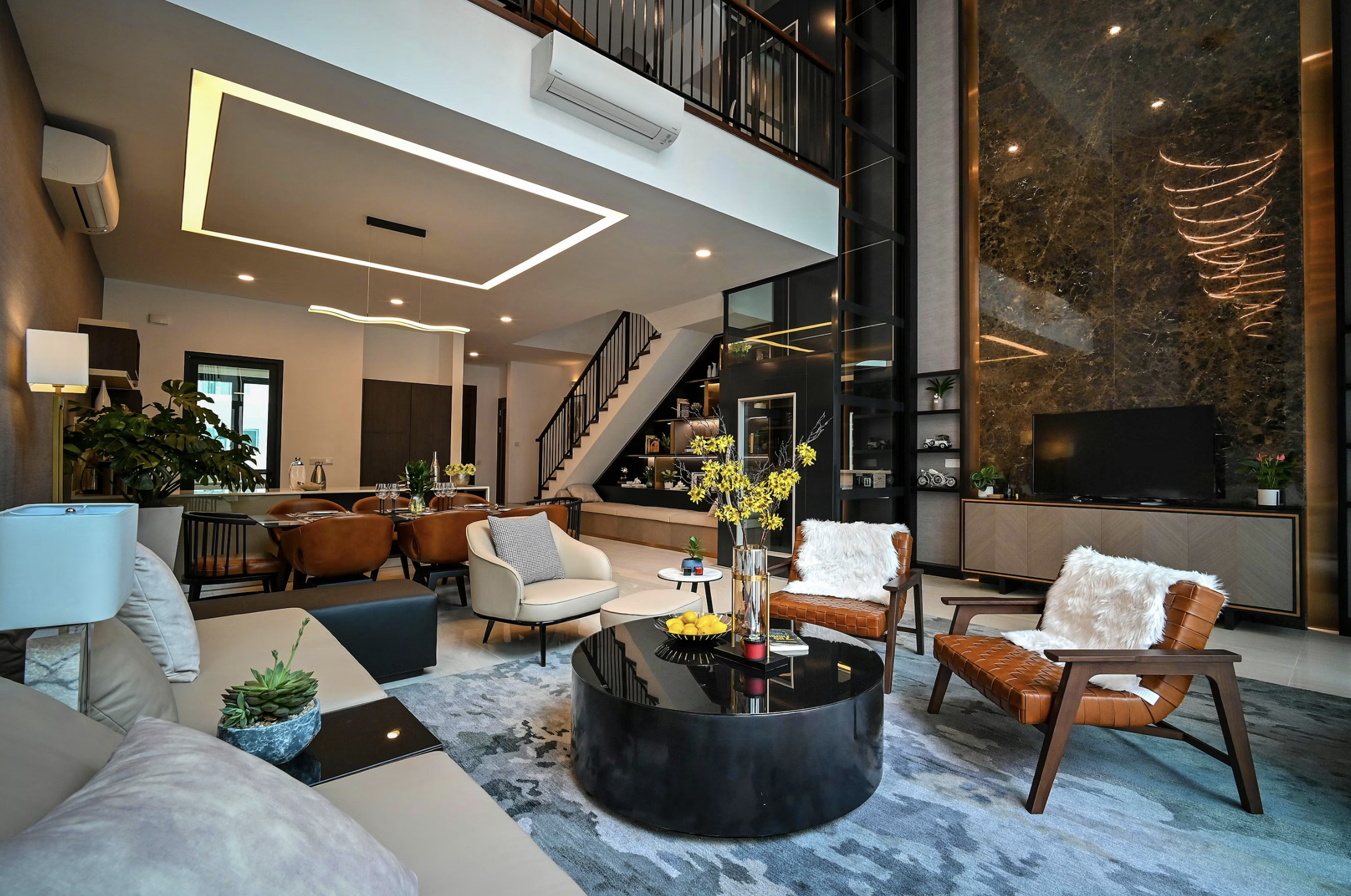 Luxurious open-plan living room with curved leather chairs, a black glossy coffee table, and a marble wall with warm lighting fixtures.
