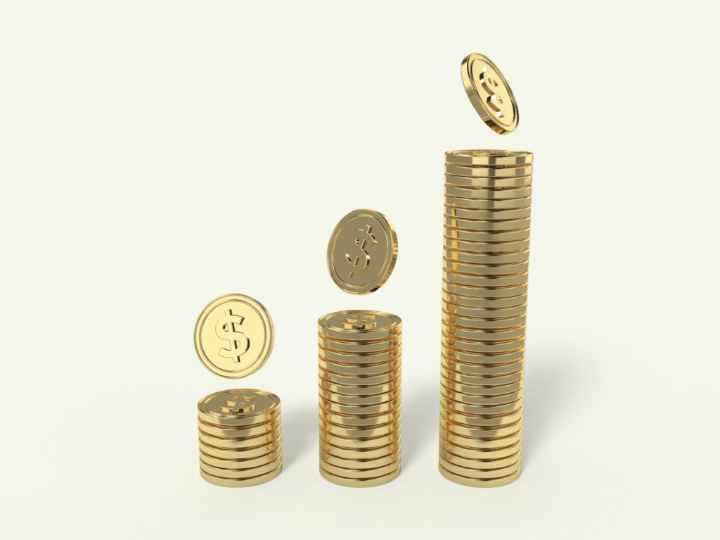 Stack of shiny gold coins stacked tall, with a few coins floating nearby against a pale background (wealth/savings theme).