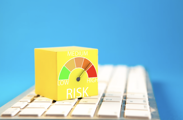 Yellow box with a colorful risk gauge pointing to medium, labeled 'MEDIUM' beside a keyboard against a blue background.