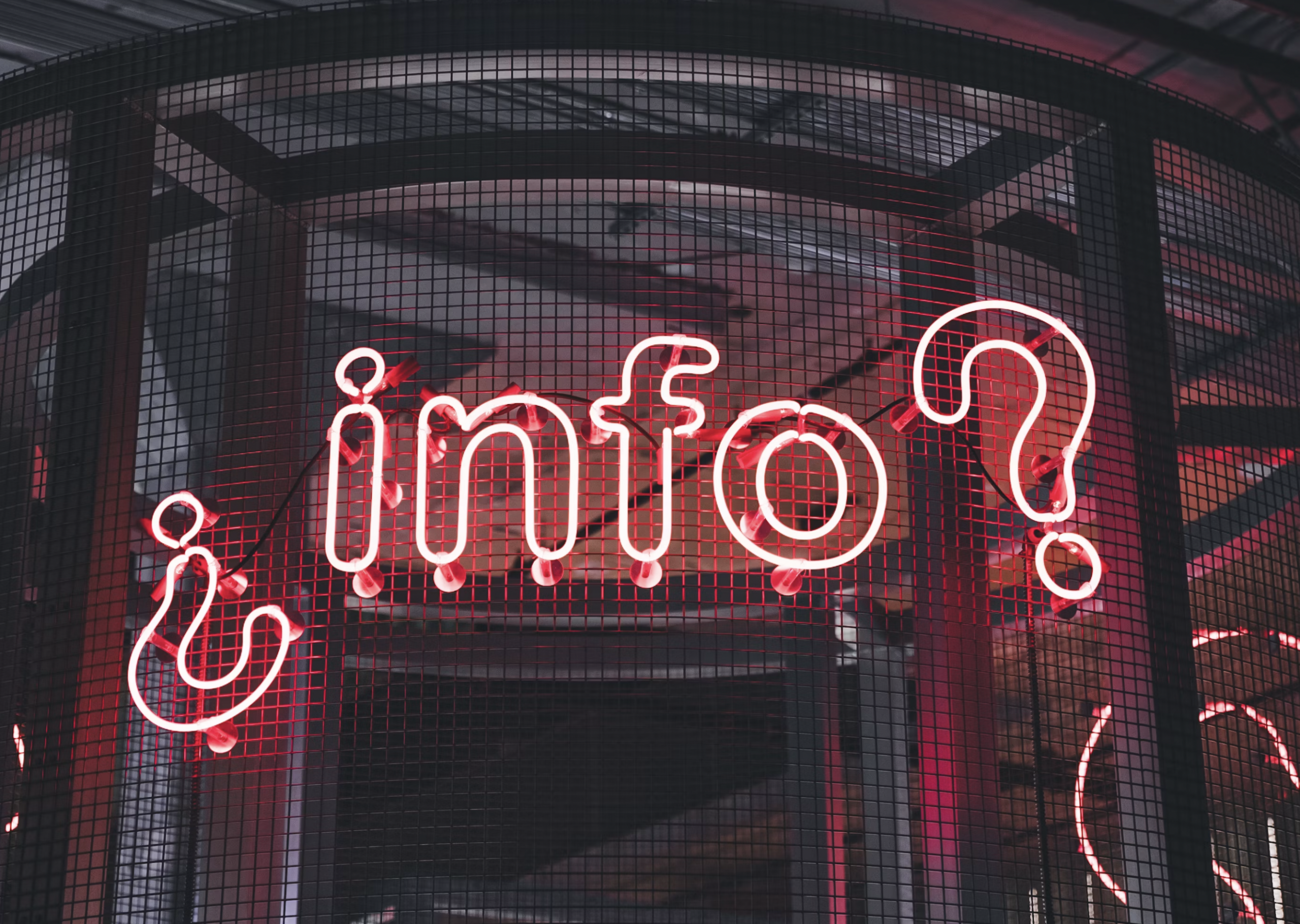 Pink neon cursive sign visible through a metal grid in a dark interior.