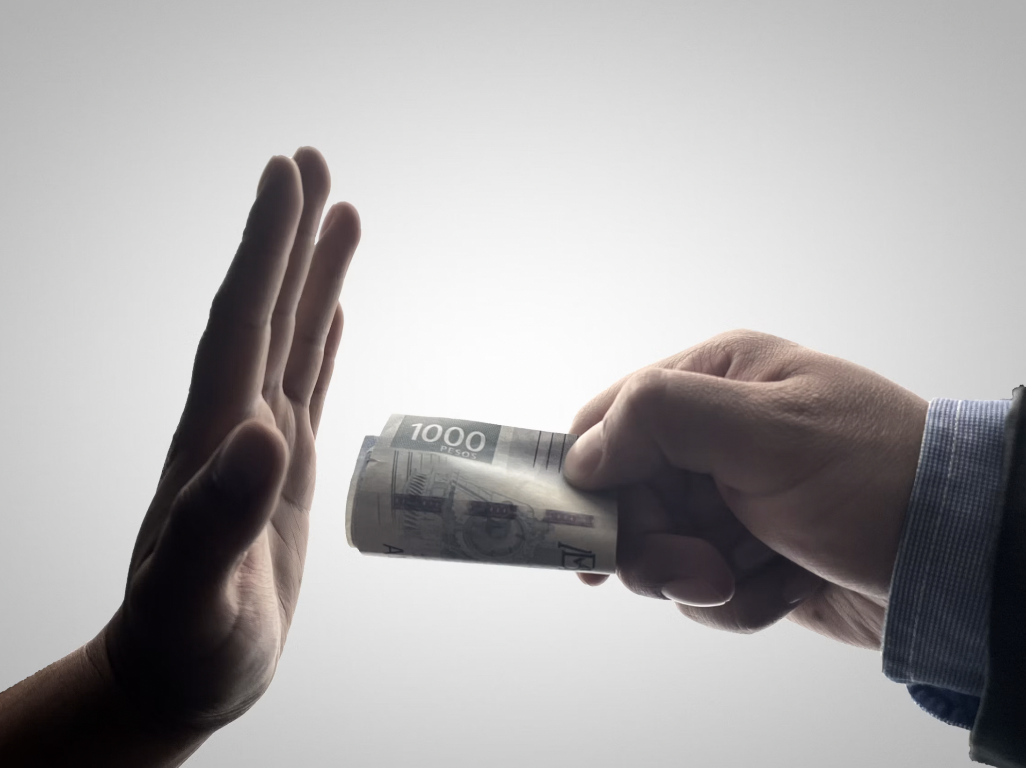 Two hands are exchanging a roll of 1000-peso banknotes; one hand holds the bills while the other is open to receive them.